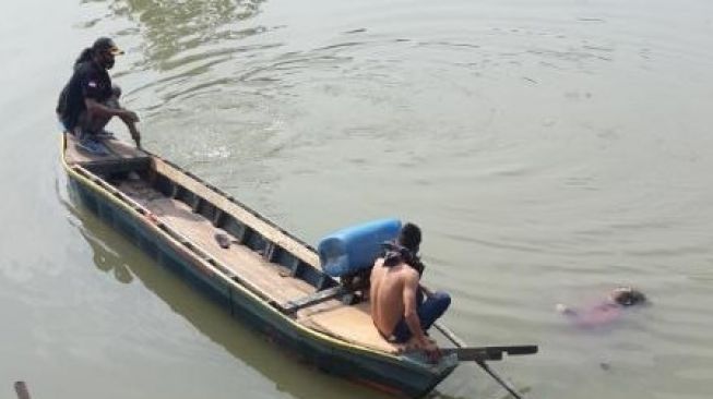 Sejumlah warga tengah mengevakuasi mayat yang mengapung di aliran sungai Cisadane, Kota Tangerang, Kamis, (10/9/2020). [Suara.com/Irfan Maulana]