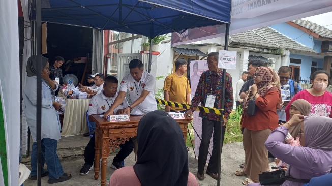 Petugas KPPS sedang melayani calon pemilih di salah satu TPS Pekanbaru, Rabu (14/2/2024). [Suara.com/Eko Faizin]